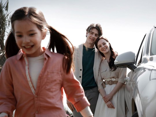 Ett barn och två vuxna befinner sig vid sidan om en vit Hyundai SANTA FE.