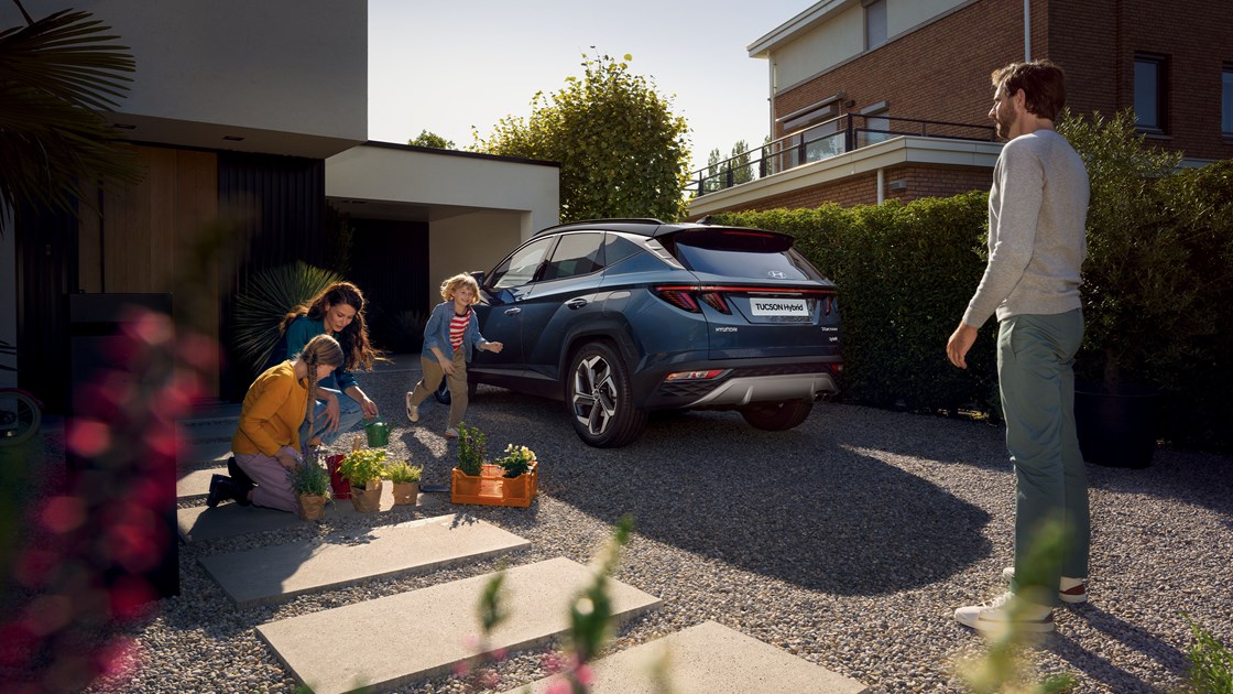 En familj och en hybrid från Hyundai på en garageuppfart.