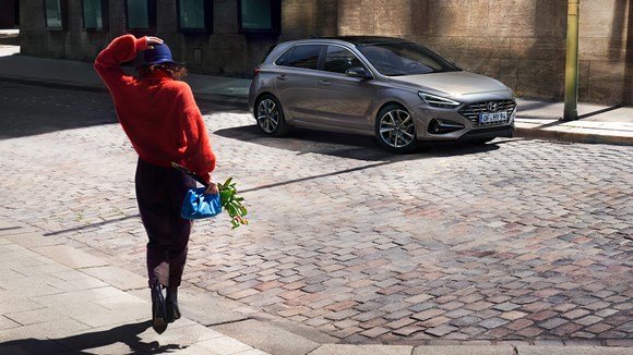 Kvinna och Hyundai i30 mildhybrid i stadsmiljö.