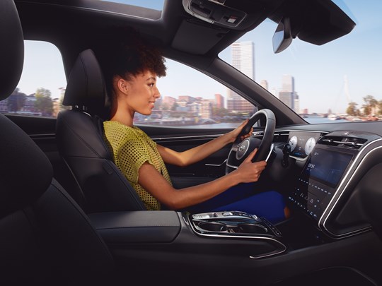 Kvinna körandes Hyundai SUV laddhybrid i stadsmiljö.