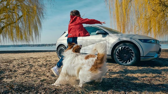 Barn och hund vid Hyundai IONIQ 5 elbil i natur miljö.