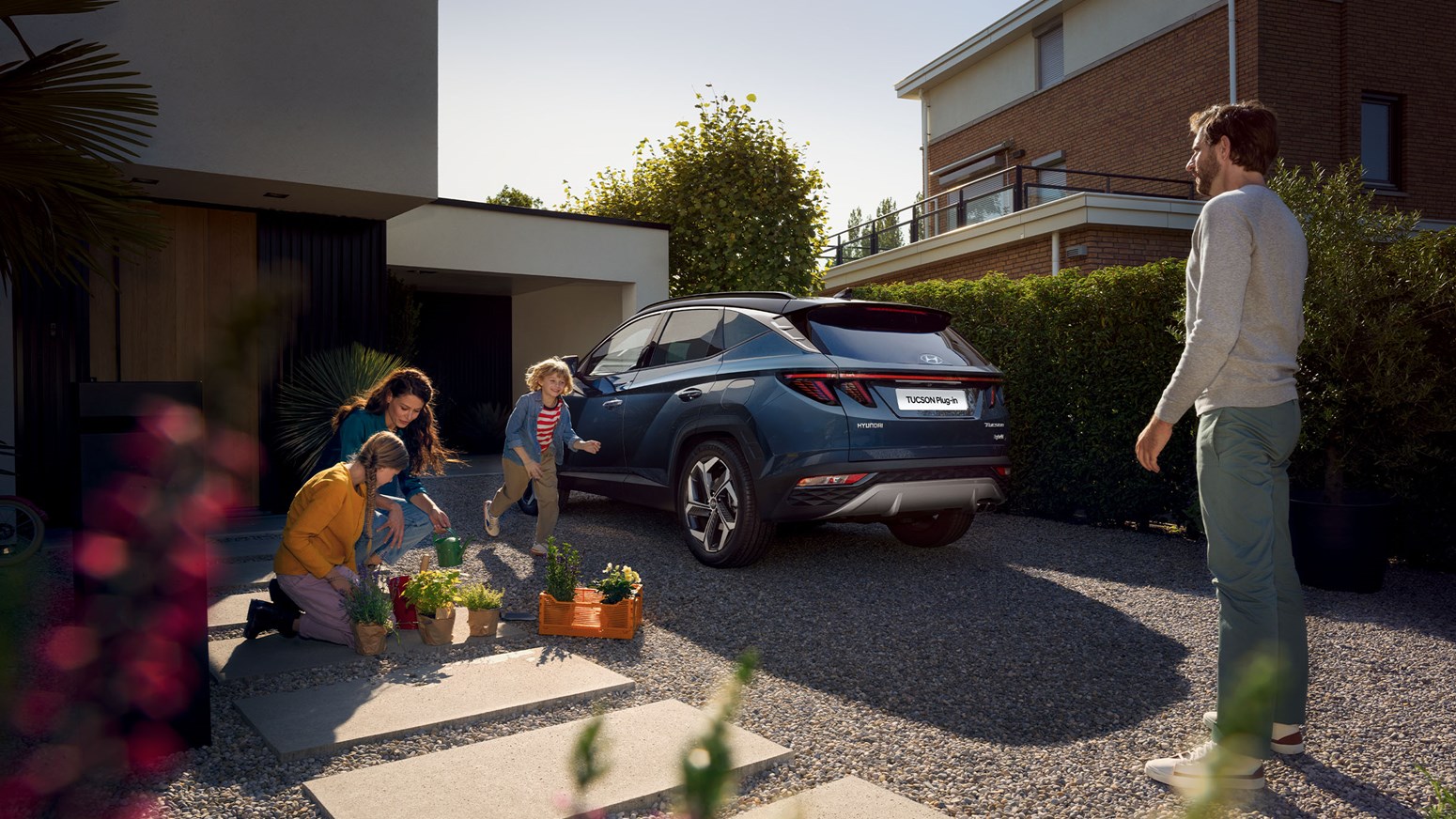 Familj med Hyundai TUCSON Plug-in Hybrid SUV på uppfart.